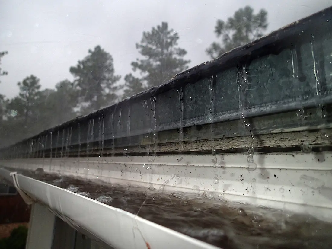 gouttière de toit sous la pluie, eau qui déborde